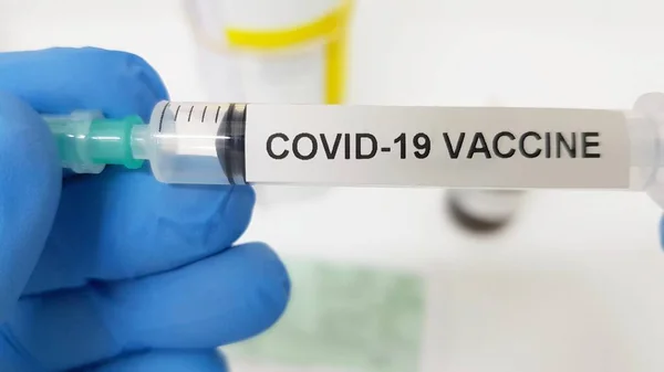 Mavi koruyucu eldivenli bir el, araştırılmış bir koronavirüs aşısını tutuyor.