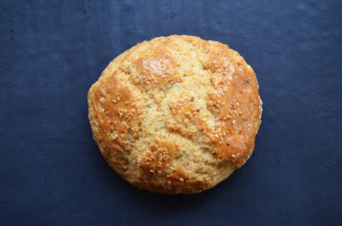 Siyah arka planda susam tohumları serpiştirilmiş çörek.