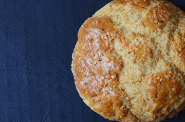 Siyah arka planda susam tohumları serpiştirilmiş çörek.