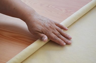 Tahta masada merdaneyle hamuru açan bir kadın..