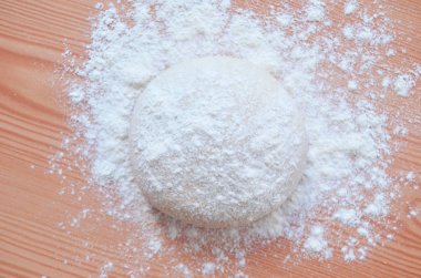 Tahta masada merdaneyle hamuru açan bir kadın..