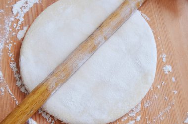 Tahta masada merdaneyle hamuru açan bir kadın..