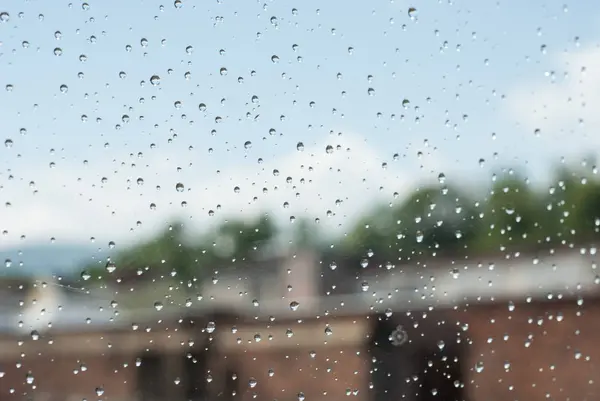 Raindrops od window glass with industrial buildings and chimneys — Stock Photo, Image