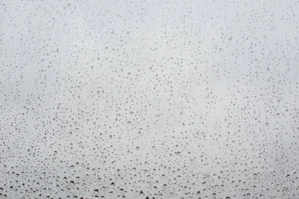 Gotas de lluvia en vidrio de ventana con cielo nublado como fondo —  Fotos de Stock