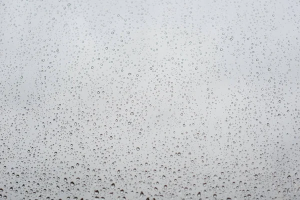 Gotas de lluvia en vidrio de ventana con cielo nublado como fondo — Foto de Stock