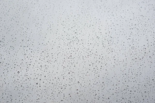 Gotas de lluvia en vidrio de ventana con cielo nublado como fondo —  Fotos de Stock