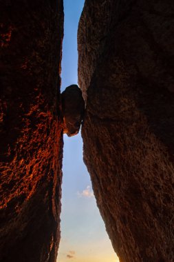 İki kayanın arasına sıkışmış kaya silueti.