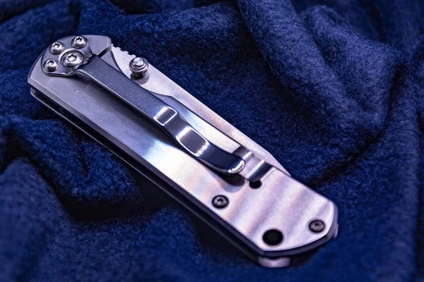 Light steel folding knife on dark background