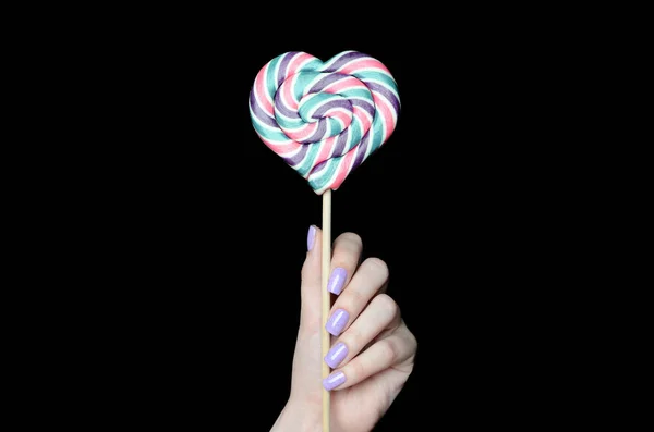 Hand holds a large lollipop in the shape of a heart — Stock Photo, Image