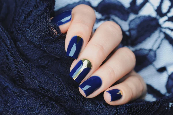 blue manicure with gold details against the background of lace