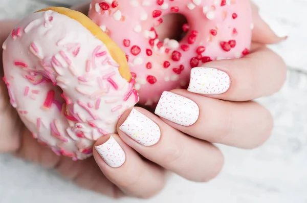 Manicure padrão branco com um donut rosa — Fotografia de Stock
