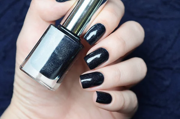 Dark blue manicure with nail polish bottle in hand — 스톡 사진