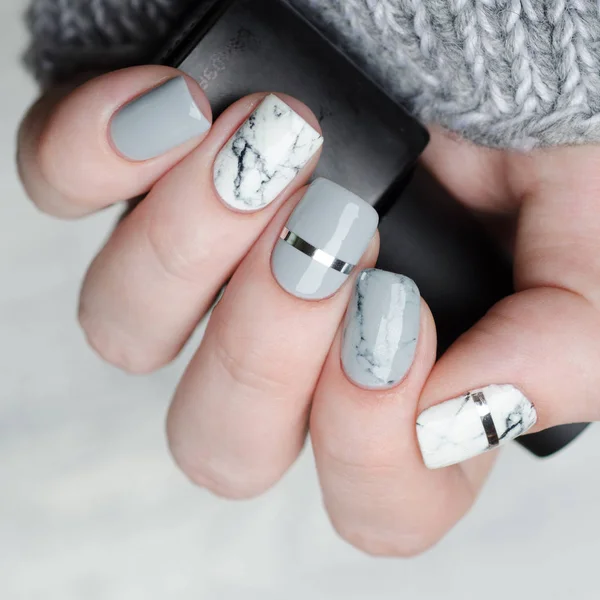 Maniküre aus weißgrauem Marmor mit silbernem Streifen auf grauem Hintergrund — Stockfoto
