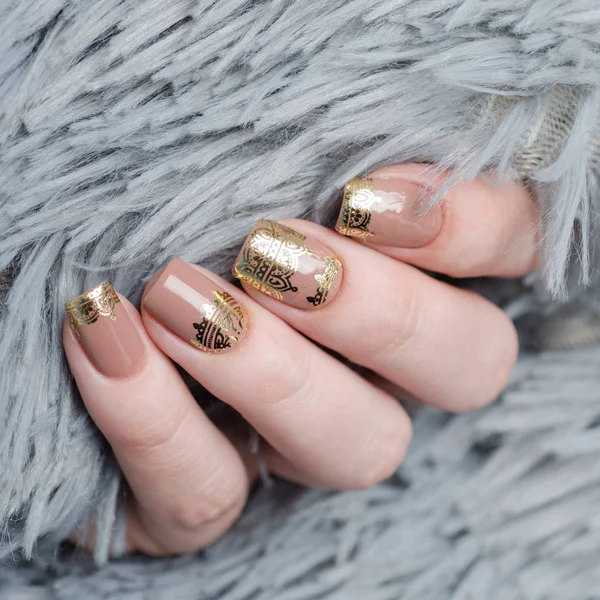 Beige Nude manicure with gold lace pattern on a gray background — Stock Photo, Image