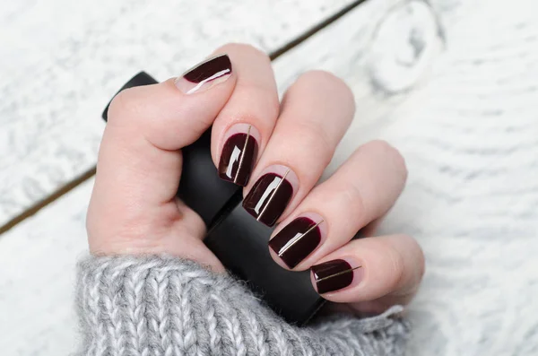 Burgundy manicure with negative space and Golden line on grey background — Stock Photo, Image