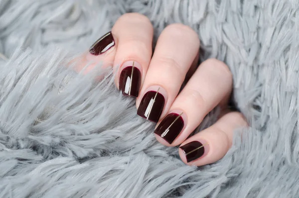 Manicure burgundowy z negatywną przestrzenią i złotą linią na szarym tle — Zdjęcie stockowe