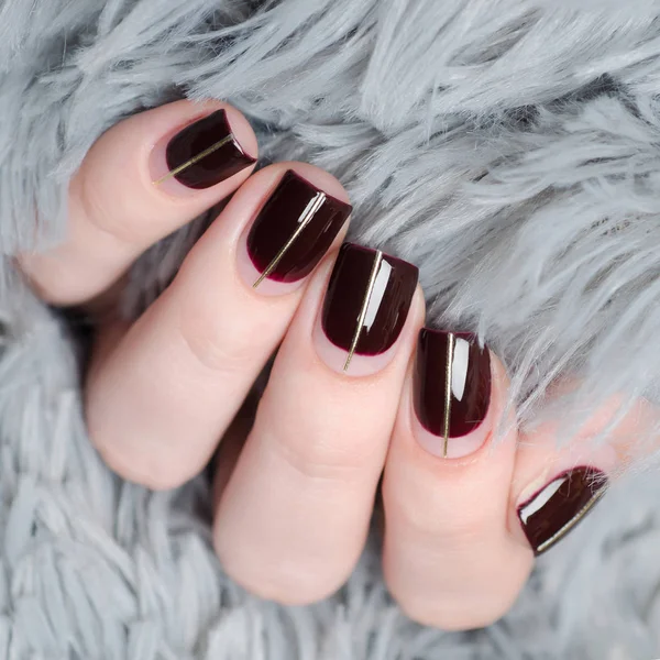 Burgundy manicure with negative space and Golden line on grey background