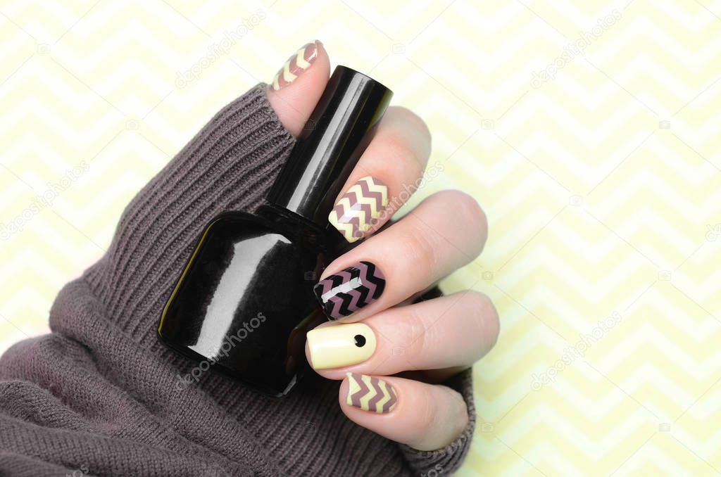 Yellow manicure with zigzag and a dot pattern on yellow background