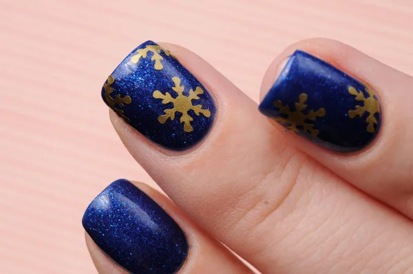 Manicura azul de invierno con patrón de brillo y copos de nieve sobre fondo de caramelo de líneas rojas —  Fotos de Stock