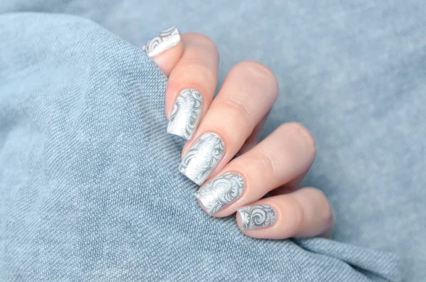 Grey winter manicure with a ftosty pattern shimmer on a gray background 스톡 사진