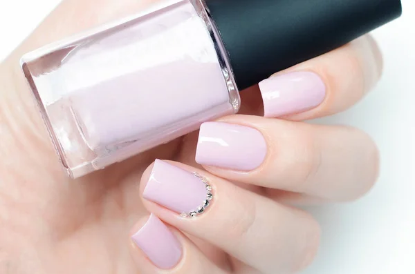 Delicate pastel pink manicure with rhinestones on white background 스톡 사진