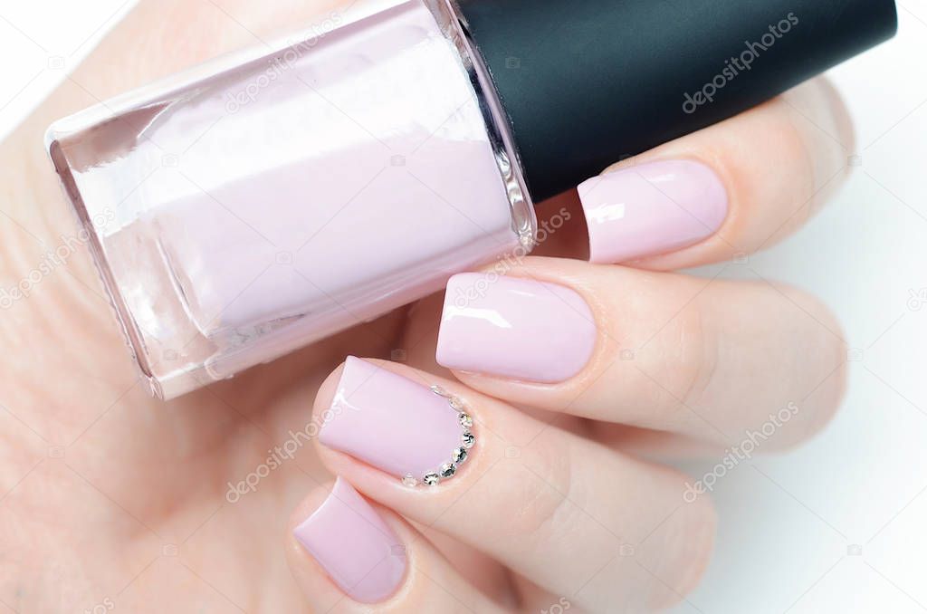 Delicate pastel pink manicure with rhinestones on white background