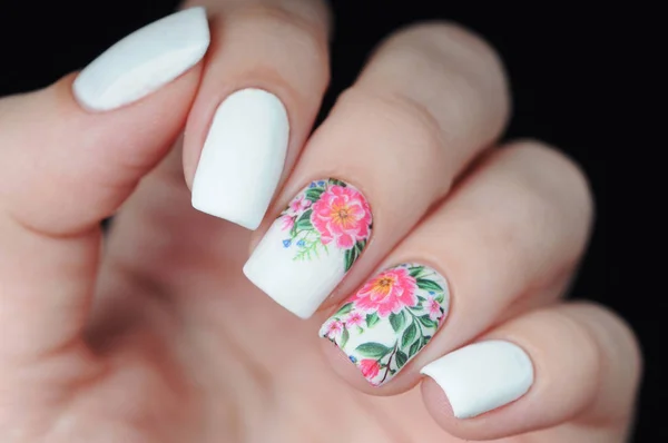 Manicura branca com estampa floral rosa e verde sobre fundo preto Fotografias De Stock Royalty-Free