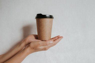 Elinde kahve ya da çayla kağıt bardak tutan bir kadın. Kahve zamanı. Tek kullanımlık kağıt bardak. Güzel sarı saçlı genç kız. Sıradan tarz, beyaz gömlek ve kot pantolon. Götürün. Sıcak içecek. Boşluk alanı