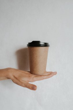Elinde kahve ya da çayla kağıt bardak tutan bir kadın. Kahve zamanı. Tek kullanımlık kağıt bardak. Güzel sarı saçlı genç kız. Sıradan tarz, beyaz gömlek ve kot pantolon. Götürün. Sıcak içecek. Boşluk alanı