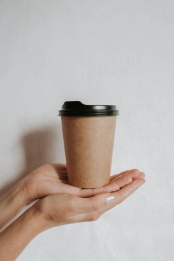 Elinde kahve ya da çayla kağıt bardak tutan bir kadın. Kahve zamanı. Tek kullanımlık kağıt bardak. Güzel sarı saçlı genç kız. Sıradan tarz, beyaz gömlek ve kot pantolon. Götürün. Sıcak içecek. Boşluk alanı