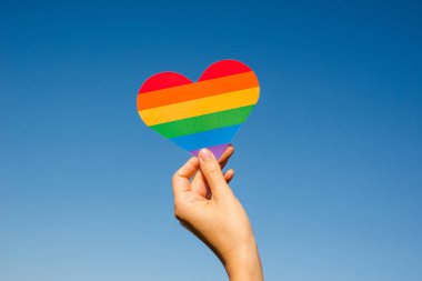 Kadın elinde gökkuşağının renginde bir kalp tutuyor. Genç, güzel bir kız. Lgbt tarihi ayı. Gurur Ayı. Lezbiyen Gey Biseksüel Transseksüel. Lgbt bayrağı. Aşk, insan hakları, hoşgörü. Lgbtq+