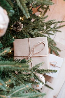 Noel ağacının yanında çelenkler ve oyuncaklarla Noel hediyeleri. Evde tatil için hediye kutuları var. Güzel mutlu ışıklar. Boks günü, yeni yıl ve Noel için sürpriz. Kraft ambalaj kağıdı ve sicim