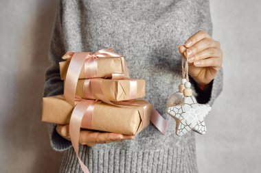 Kadın elinde bir Noel hediyesi tutuyor. Mutlu tatiller, hediye kutusu yakın çekimi. Boks günü, Noel ve yeni yıl partisi için sürpriz. Sihir zamanı. Kış kutlamaları. Paket kağıdı, oyuncaklar ve kurdele