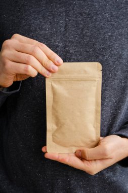 Kraft paper packaging in a mans hands. Packaging for coffee, cosmetics. Packing closeup. Product for sale. Online shopping. Boxes with surprise. Delivery service, shipping. Empty, mockup. Eco friendly