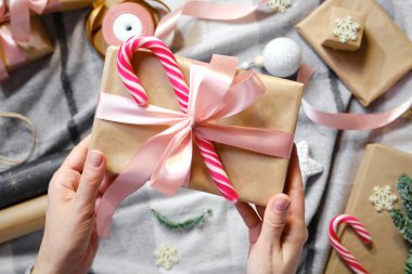 Kadın elinde bir Noel hediyesi tutuyor. Mutlu tatiller, hediye kutusu yakın çekimi. Boks günü, Noel ve yeni yıl partisi için sürpriz. Sihir zamanı. Kış kutlamaları. Paket kağıdı, oyuncaklar ve kurdele