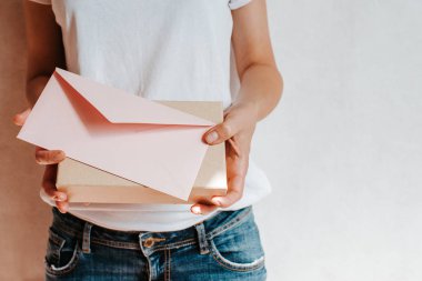 Kadın el kâğıdı zarf ve kutu tutuyor. Yeni posta, mesaj. Posta servisi. Genç kız mektup ya da paket istiyor. Boş zarf, boş alan. İnsanlarla iletişim. Zarf kapatma