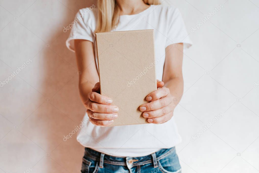 Woman holding in hand small paper box. Young girl with new package. Postal service, delivery. Craft paper. Gift box, present. Box closeup. Blank packing, empty space. People communication. Carton case