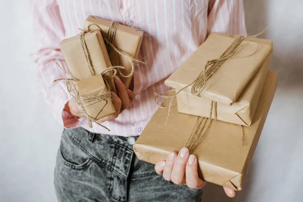 Woman holding many gift boxes in hand. Holiday present. Boxes with surprise. Happy celebration event. Kraft paper packaging. Wrapping paper and ribbon. Female hand with boxes close-up. Congratulation