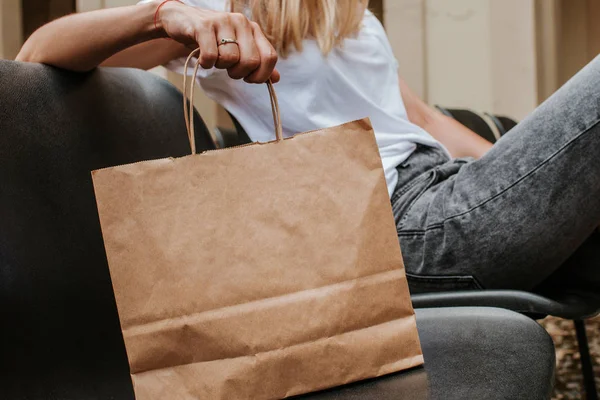 Happy blond woman with shopping package in the city. Paper bag. Sale in store. Beautiful young girl after shop. Lady buy present. Black friday sale. Holiday special offer, discount. Female love market
