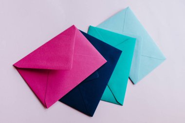 Colored paper envelopes on a light background. New mail, write message. Send and receive letter. Postal delivery service. Blank envelope, empty space. People communication, paperwork. Envelope closeup