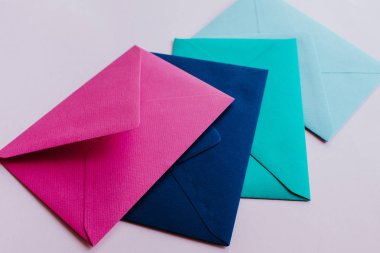 Colored paper envelopes on a light background. New mail, write message. Send and receive letter. Postal delivery service. Blank envelope, empty space. People communication, paperwork. Envelope closeup