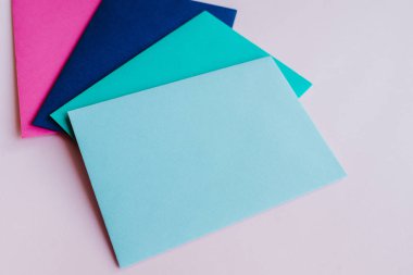 Colored paper envelopes on a light background. New mail, write message. Send and receive letter. Postal delivery service. Blank envelope, empty space. People communication, paperwork. Envelope closeup