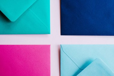 Colored paper envelopes on a light background. New mail, write message. Send and receive letter. Postal delivery service. Blank envelope, empty space. People communication, paperwork. Envelope closeup