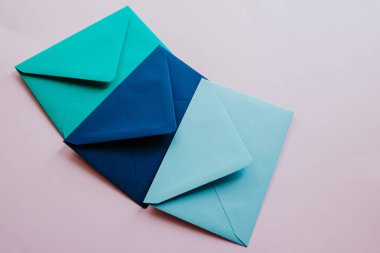 Colored paper envelopes on a light background. New mail, write message. Send and receive letter. Postal delivery service. Blank envelope, empty space. People communication, paperwork. Envelope closeup