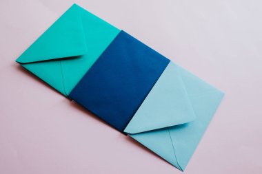 Colored paper envelopes on a light background. New mail, write message. Send and receive letter. Postal delivery service. Blank envelope, empty space. People communication, paperwork. Envelope closeup