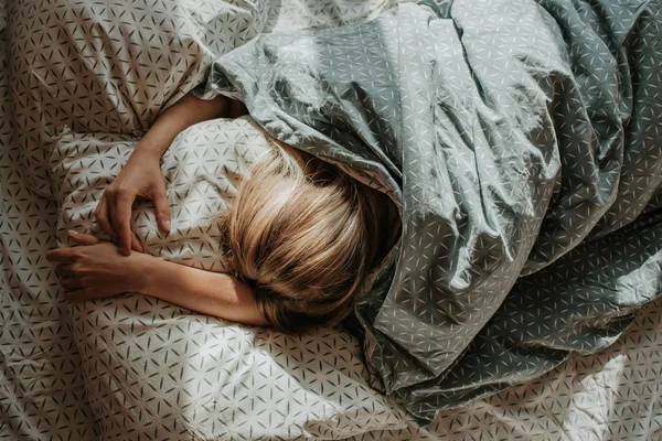 女人睡在床上金发姑娘躺在枕头上的毛毯下 醒醒吧做梦 早上好 在卧室里 舒服舒适 床单上的阳光 生活方式 — 图库照片