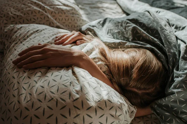 Woman sleep in bed. Blond hair girl under blanket on pillow. Wake up. Dreaming. Happy morning in bedroom. Cozy and comfortable. Sunlight on bed linen. Pillow, blanket. Recovery, relax, lifestyle
