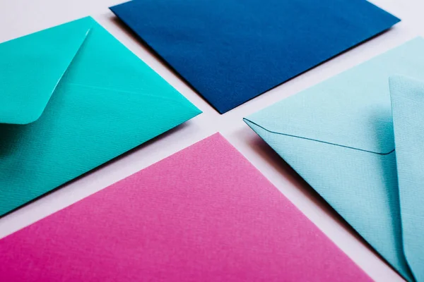 Colored paper envelopes on a light background. New mail, write message. Send and receive letter. Postal delivery service. Blank envelope, empty space. People communication, paperwork. Envelope closeup