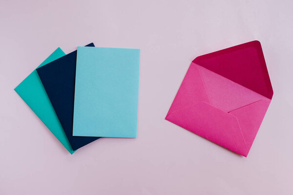 Цветные бумажные конверты на светлом фоне. Новая почта, написать сообщение. Отправить и получить письмо. Служба доставки почты. Пустой конверт, пустое место. Общение с людьми, бумажная работа. Конверт крупный план
