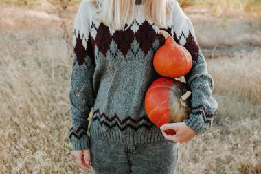 Happy blond hair women holding in hand pumpkin. Young beautiful girl in harvest. Season organic food. Autumn season. Fall color, orange and yellow. Pumpkin day and Halloween. Female in outdoor nature